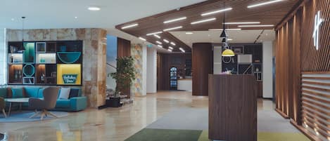 A modern lobby with a reception desk, seating area, and a large plant.