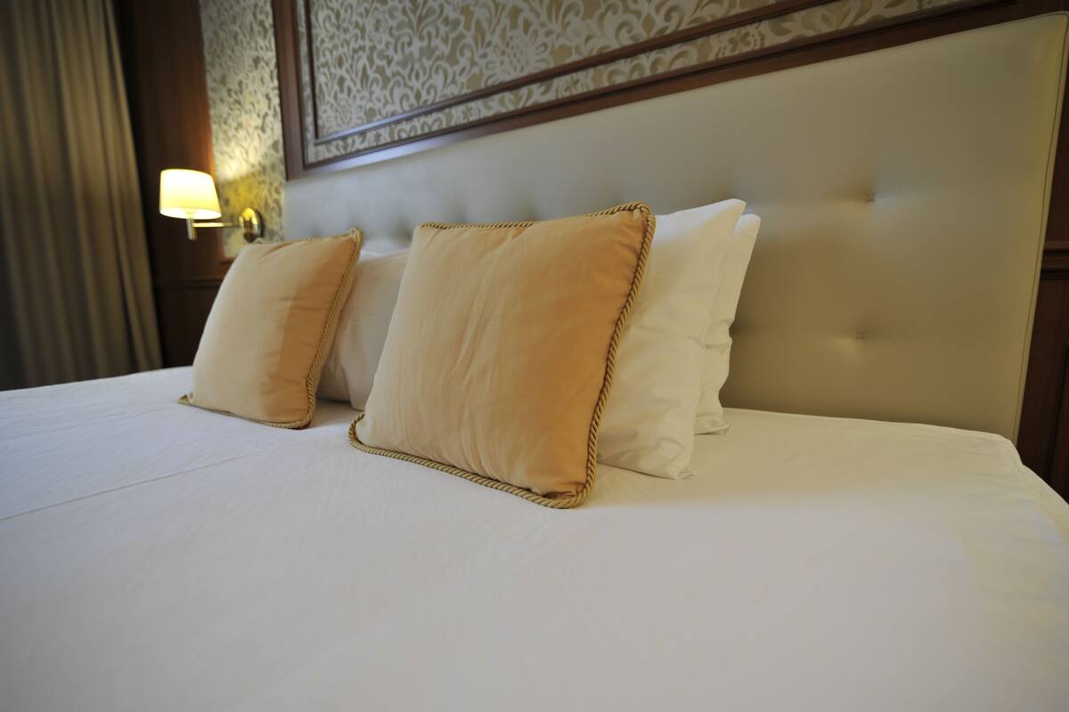 A neatly made bed with two pillows and a headboard.