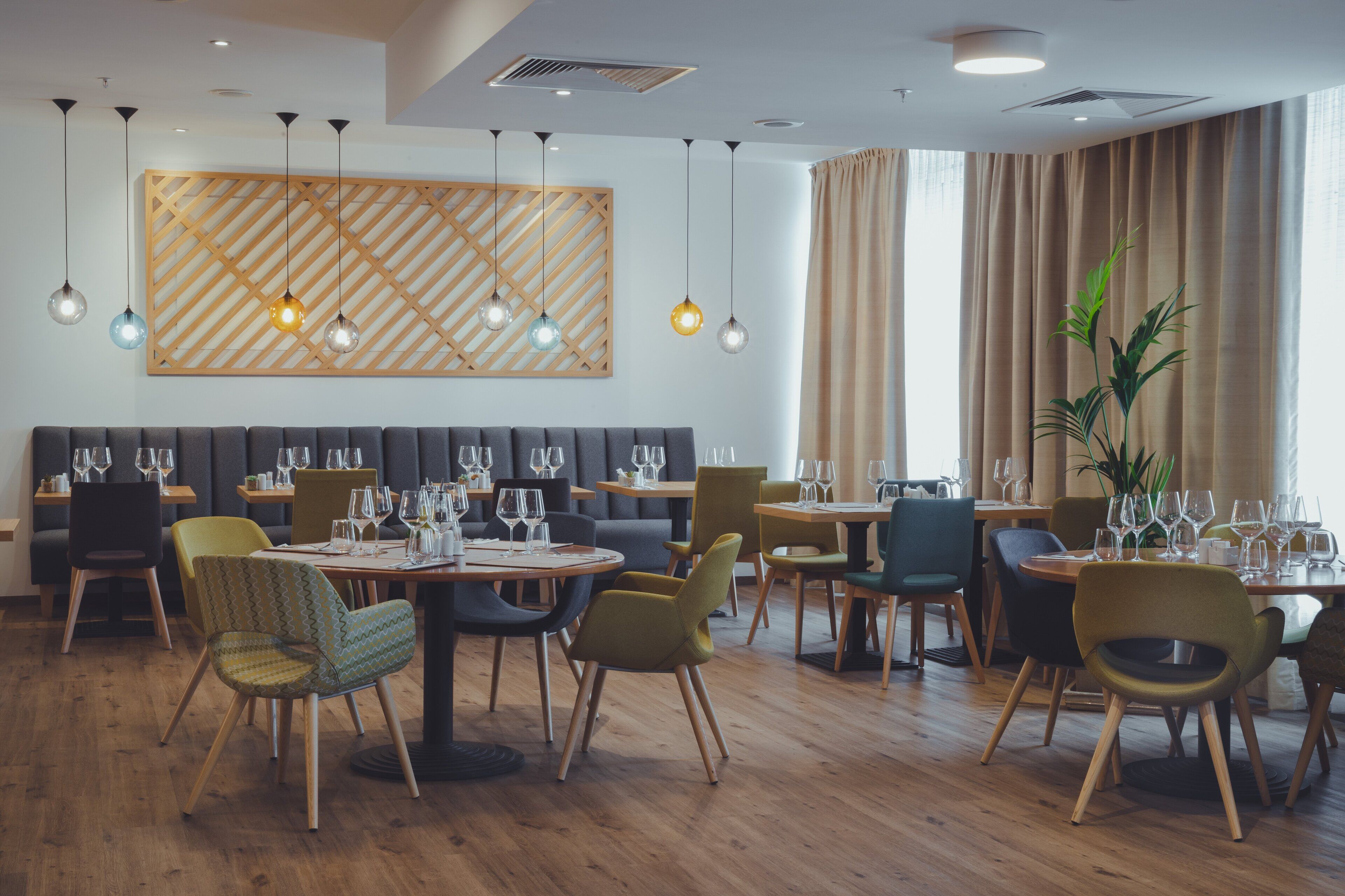 Un comedor moderno con mesas de madera, sillas tapizadas y lámparas colgantes.