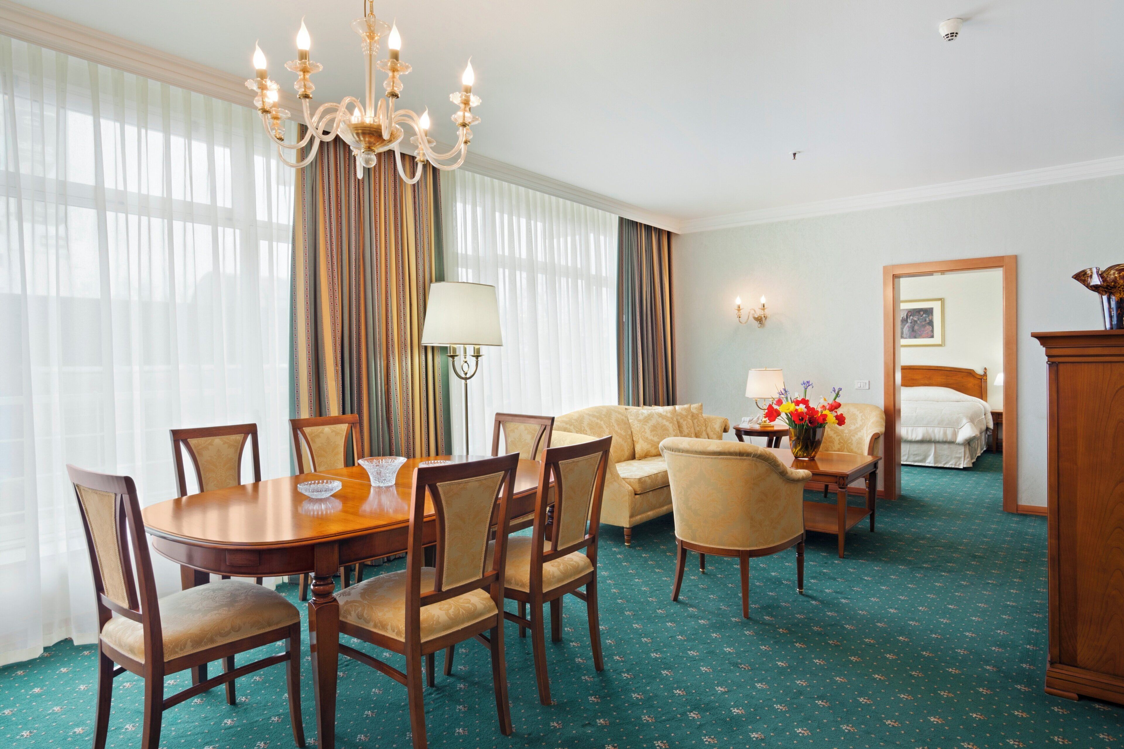 Een hotelkamer met een zithoek, een bank, een bed en een kroonluchter.