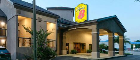 A Super 8 by Wyndham hotel with a covered entrance, outdoor seating, and a parking lot.