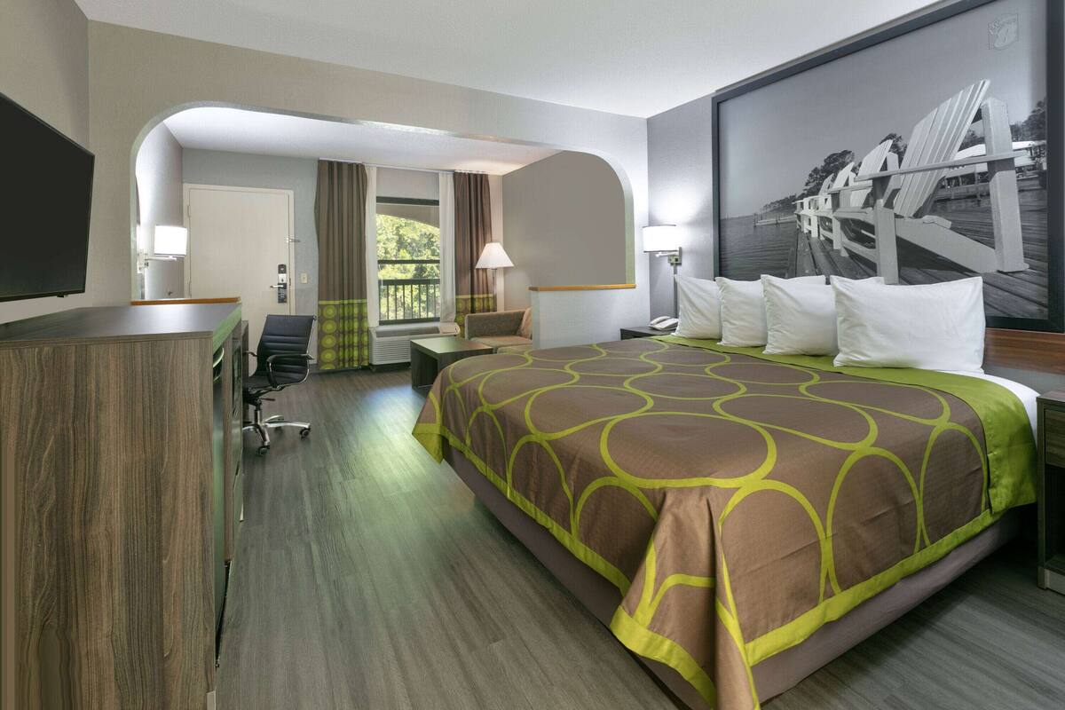 Quarto de hotel com uma cama grande, uma escrivaninha, uma cadeira e vista para o exterior.