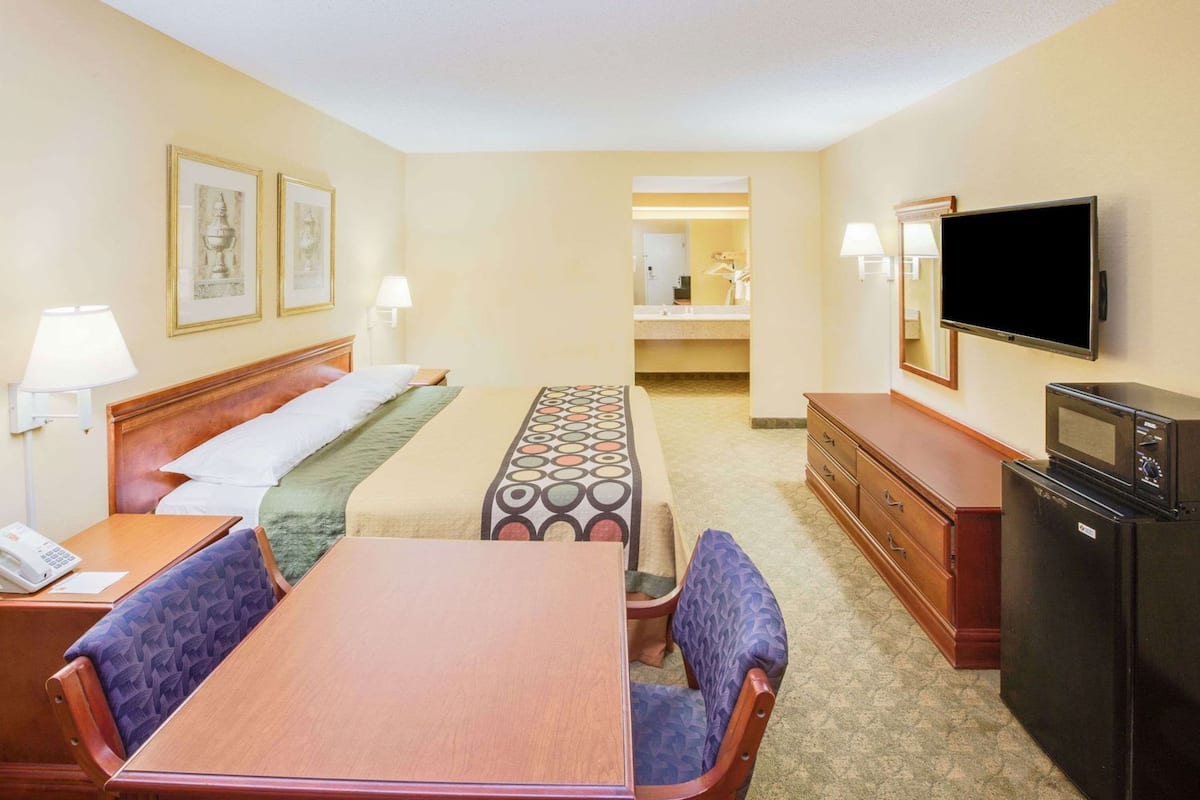 Quarto de hotel com cama, escrivaninha, telefone, televisão, micro-ondas e cómoda.