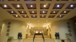 A hotel lobby with a central staircase, stone walls, and decorative elephant statues. - Elephant Hills Resort (Victoria Falls)