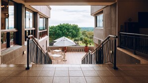 A spacious indoor area with a view of a patio and trees. - Elephant Hills Resort (Victoria Falls)
