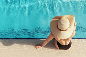 A person sitting by a pool with a clear view of the water.