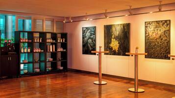 Une galerie d’art avec un plancher en bois, une bibliothèque sombre et trois tableaux accrochés au mur.