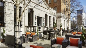 An outdoor seating area with wicker furniture and orange cushions, a staircase leading to an upper level, and a building with large windows and a brick facade. - Delta Hotels by Marriott Birmingham (Birmingham)