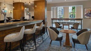 A bar area with stools, a bar counter, and a seating area with a round table and chairs. - Delta Hotels by Marriott Birmingham (Birmingham)