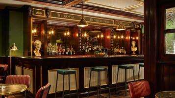 A bar area with a counter, stools, and a variety of bottles.