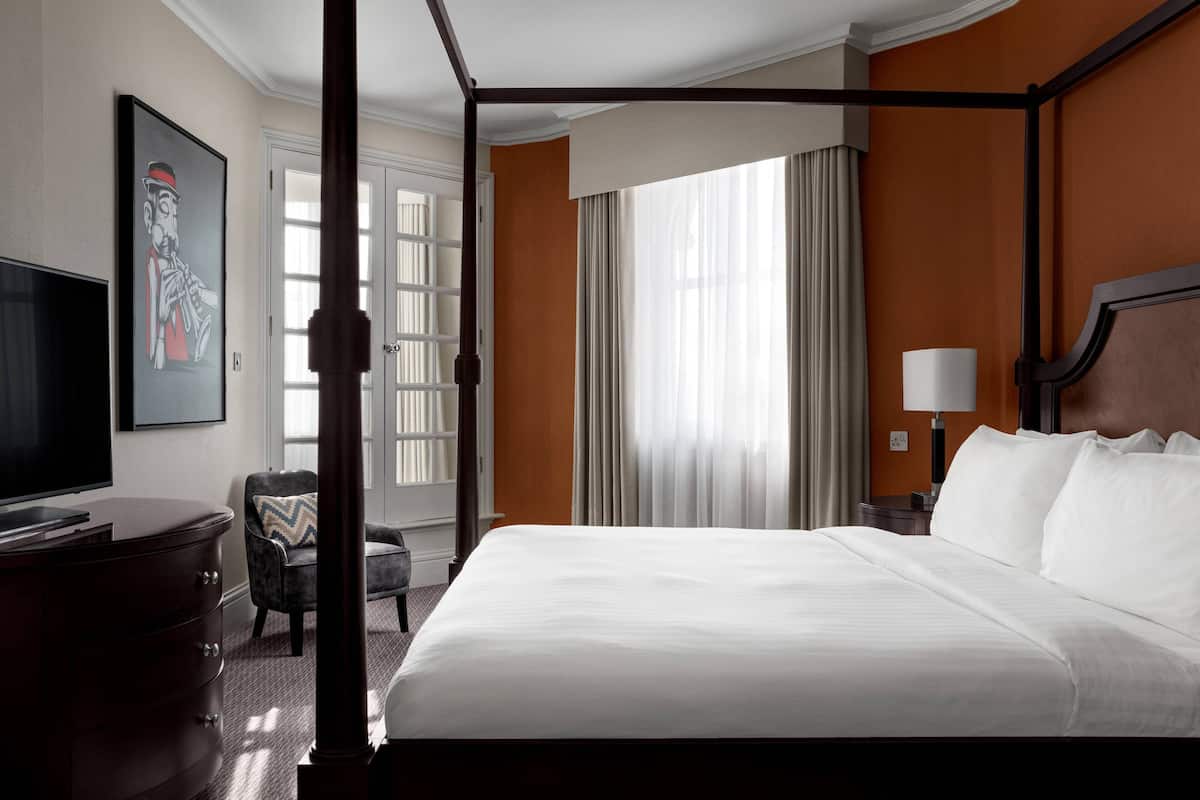 A hotel room with a large bed, a television, a desk, and a chair.