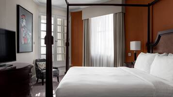Una habitación de hotel con una cama grande, televisión, escritorio y una silla.