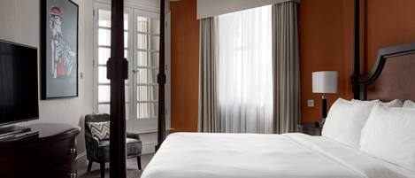 A hotel room with a large bed, a television, a desk, and a chair.