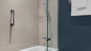 Een moderne badkamer met een douchecabine van glas, een wit bad en een handdoekrek.