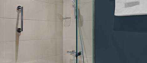 A modern bathroom with a glass-enclosed shower, a white bathtub, and a towel rack.