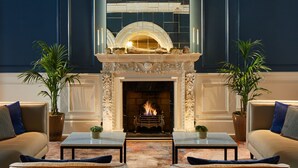 A lobby with a fireplace, two sofas, and two coffee tables.