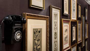 A wall with framed botanical prints and a vintage rotary phone.