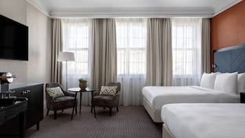 A hotel room with two beds, a TV, a desk, and a chair.