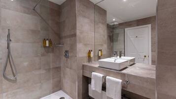Ein modernes Badezimmer mit begehbarer Dusche, einem Doppelwaschbecken und einer Toilette mit Handtuchhalter.