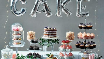 Una presentación de postres con diversos pasteles y repostería, incluyendo un pastel de varias capas con un arreglo floral.