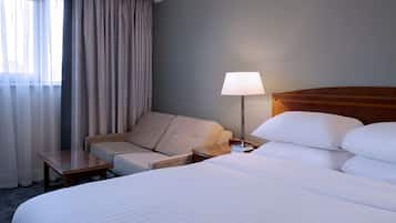 A hotel room with a large bed, a sofa, a table, and a lamp.