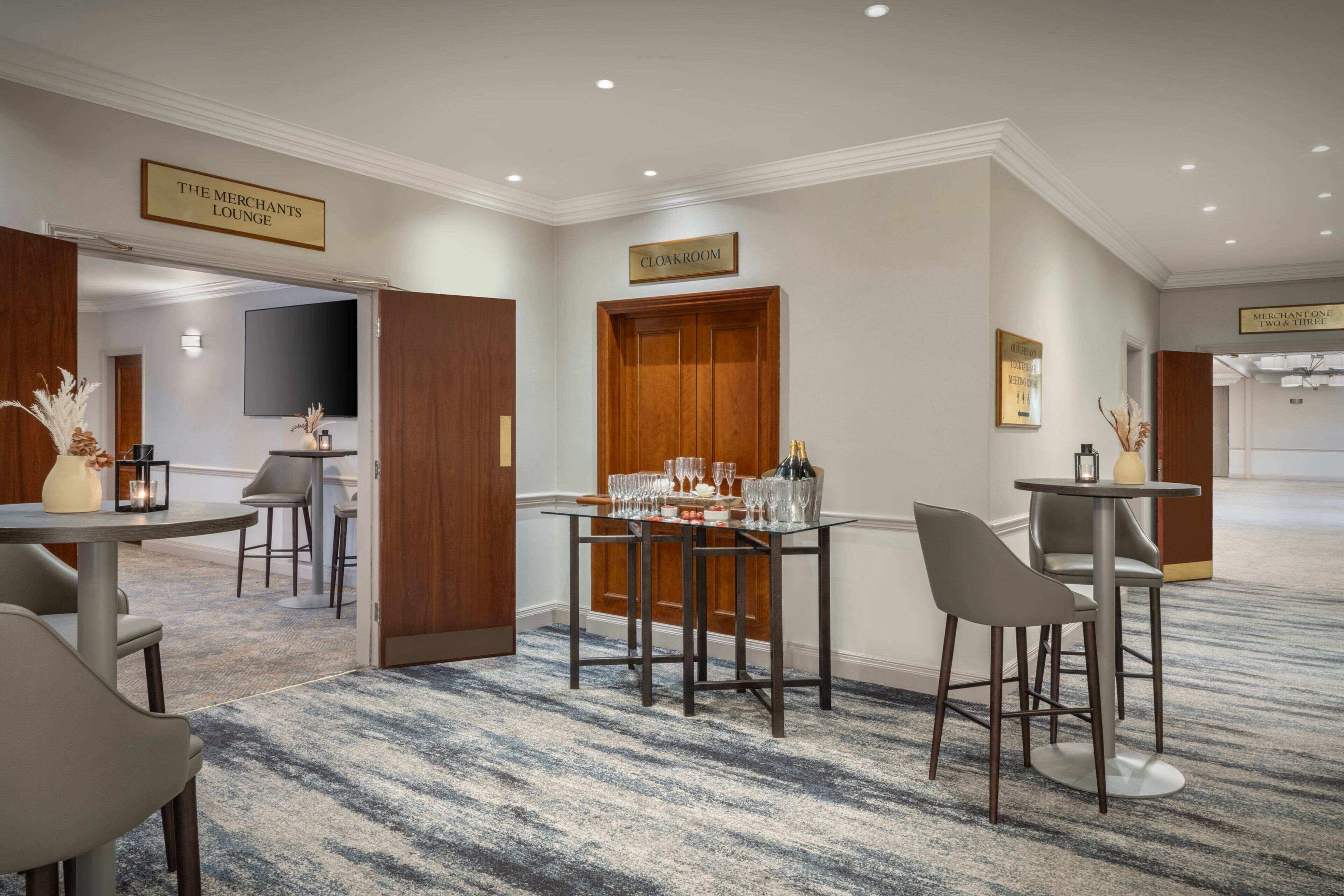 A hotel lobby with a bar area, a cloakroom, and a television screen.