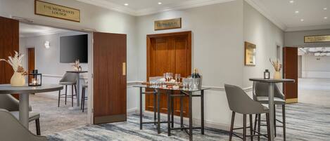 A hotel lobby with a bar area, a cloakroom, and a television screen.