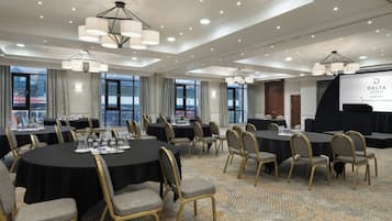 A conference room with round tables, chairs, and a large screen displaying the Delta Hotels logo.