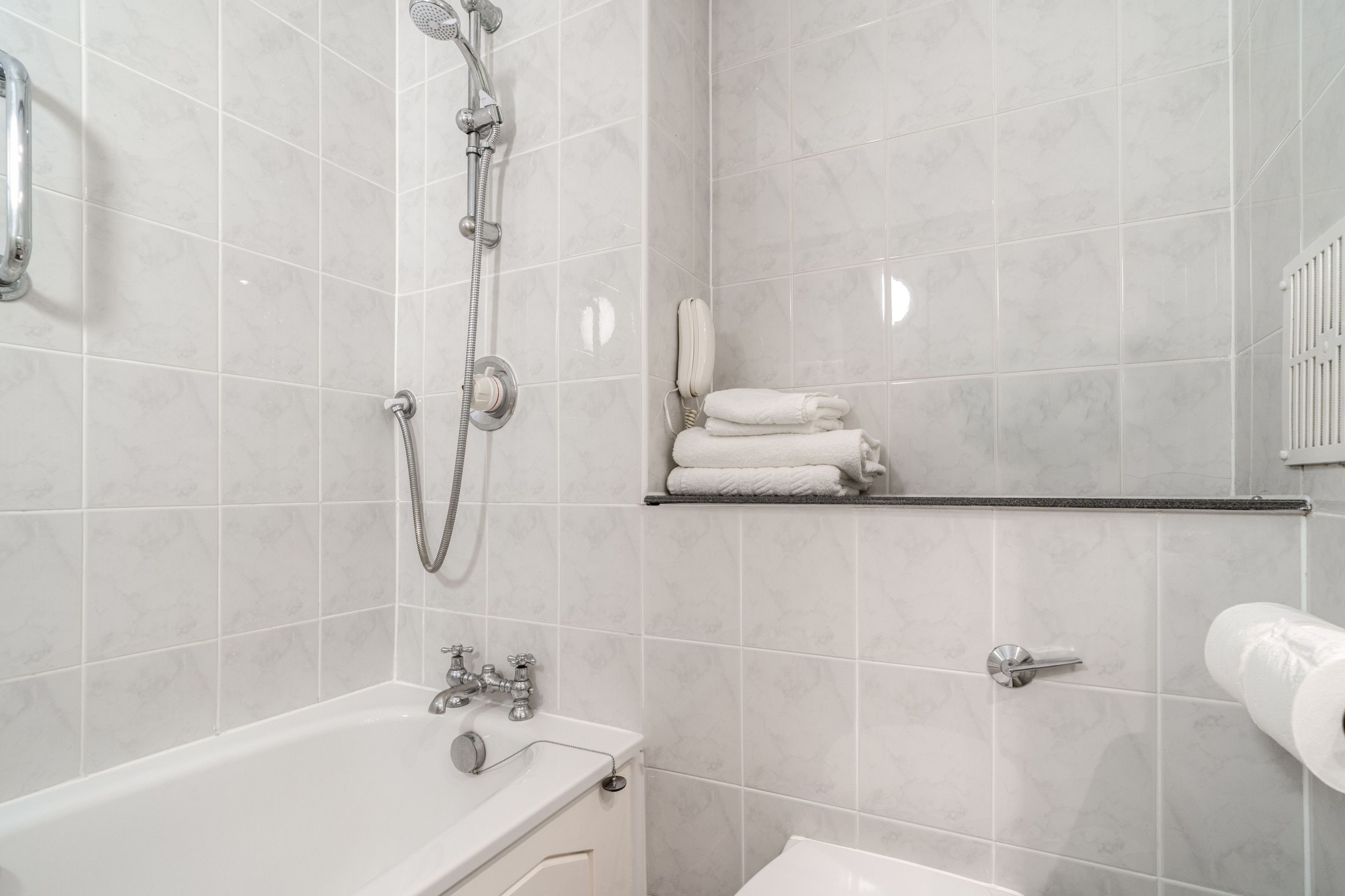 A bathroom with a bathtub, a shower, a toilet, and a towel rack.