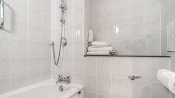 A bathroom with a bathtub, a shower, a toilet, and a towel rack.