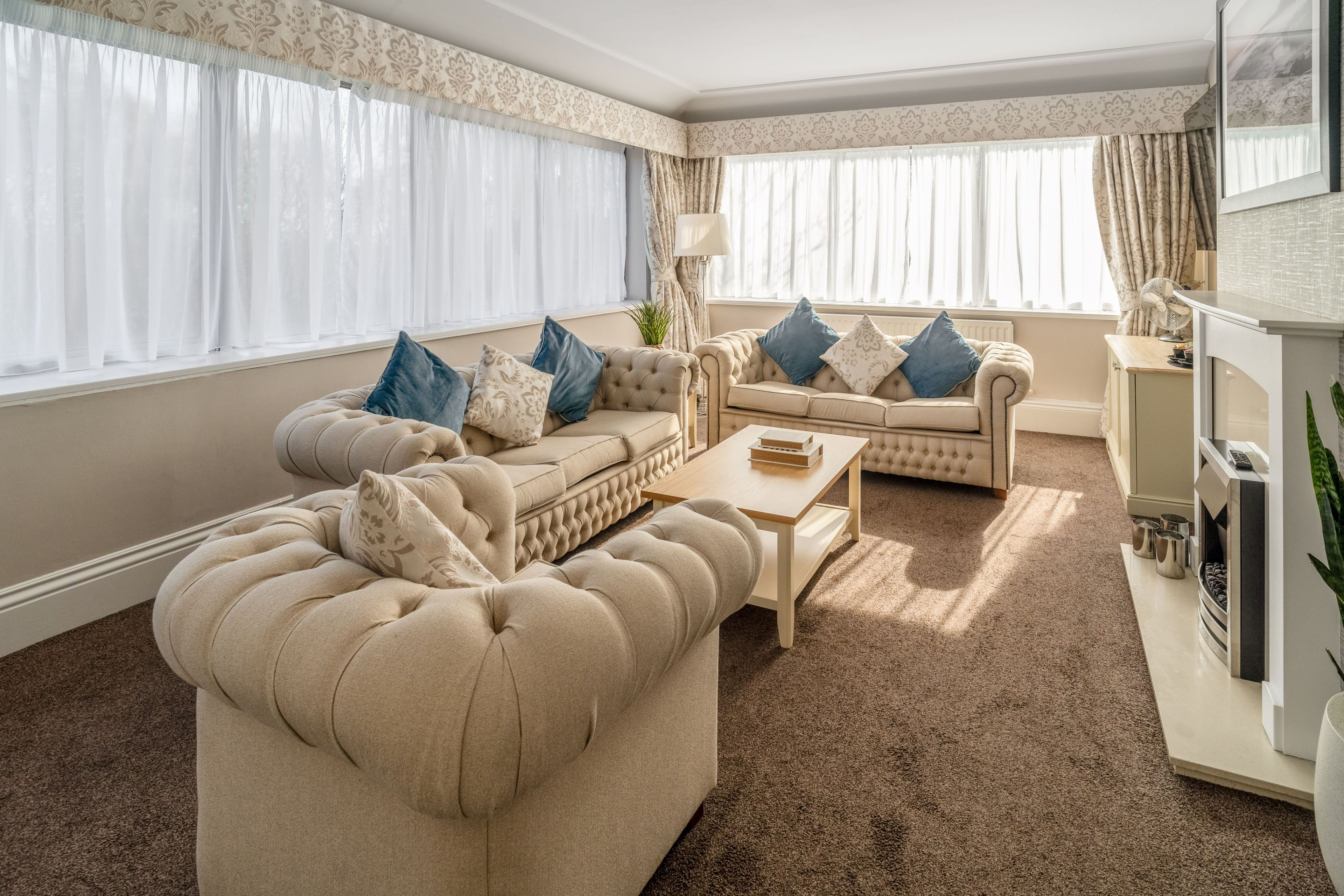A living room with a large beige sofa, a smaller sofa, a coffee table, and a fireplace.