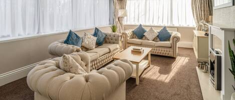 A living room with a large beige sofa, a smaller sofa, a coffee table, and a fireplace.