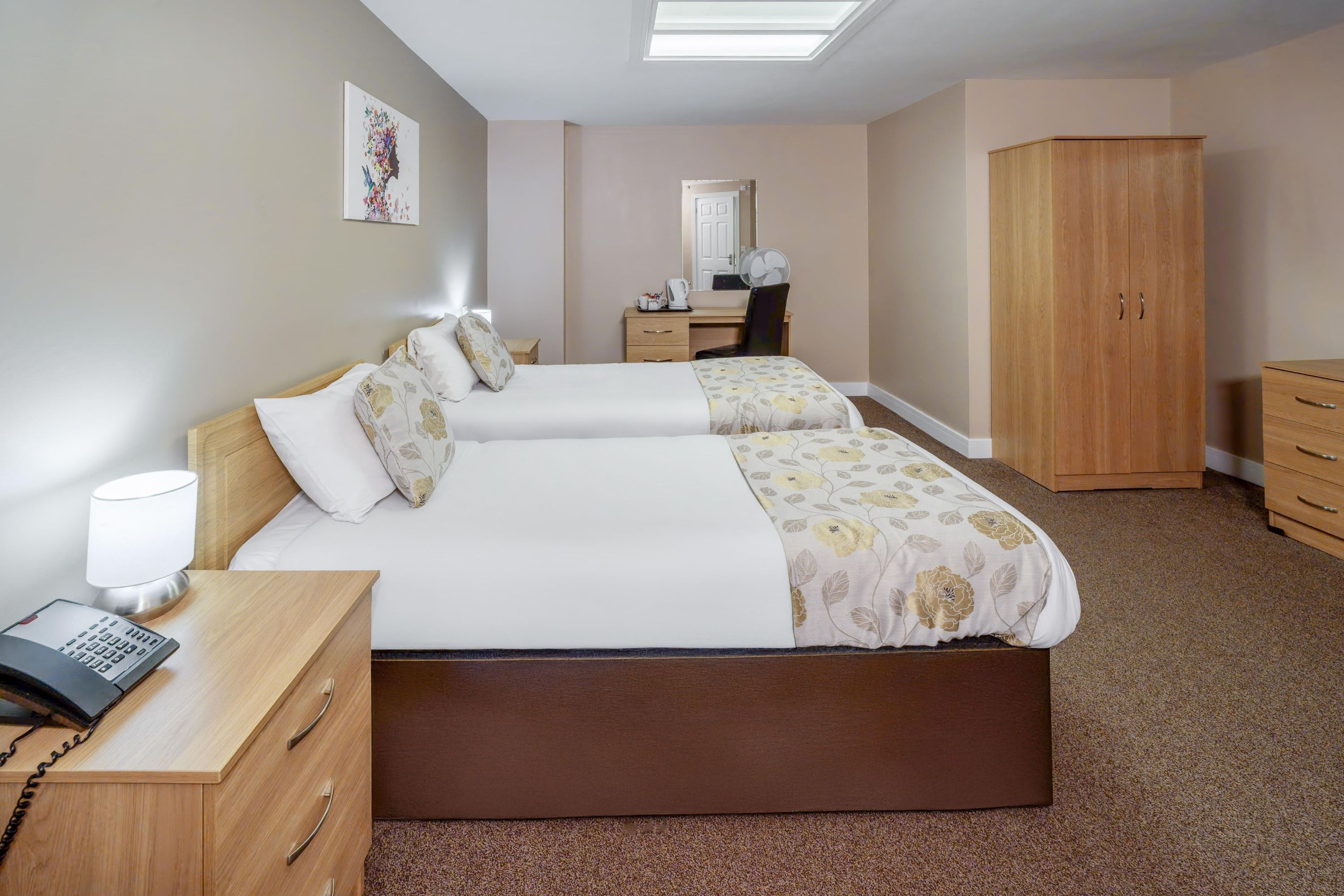 Habitación de hotel con cama, mesita de noche, lámpara y armario.