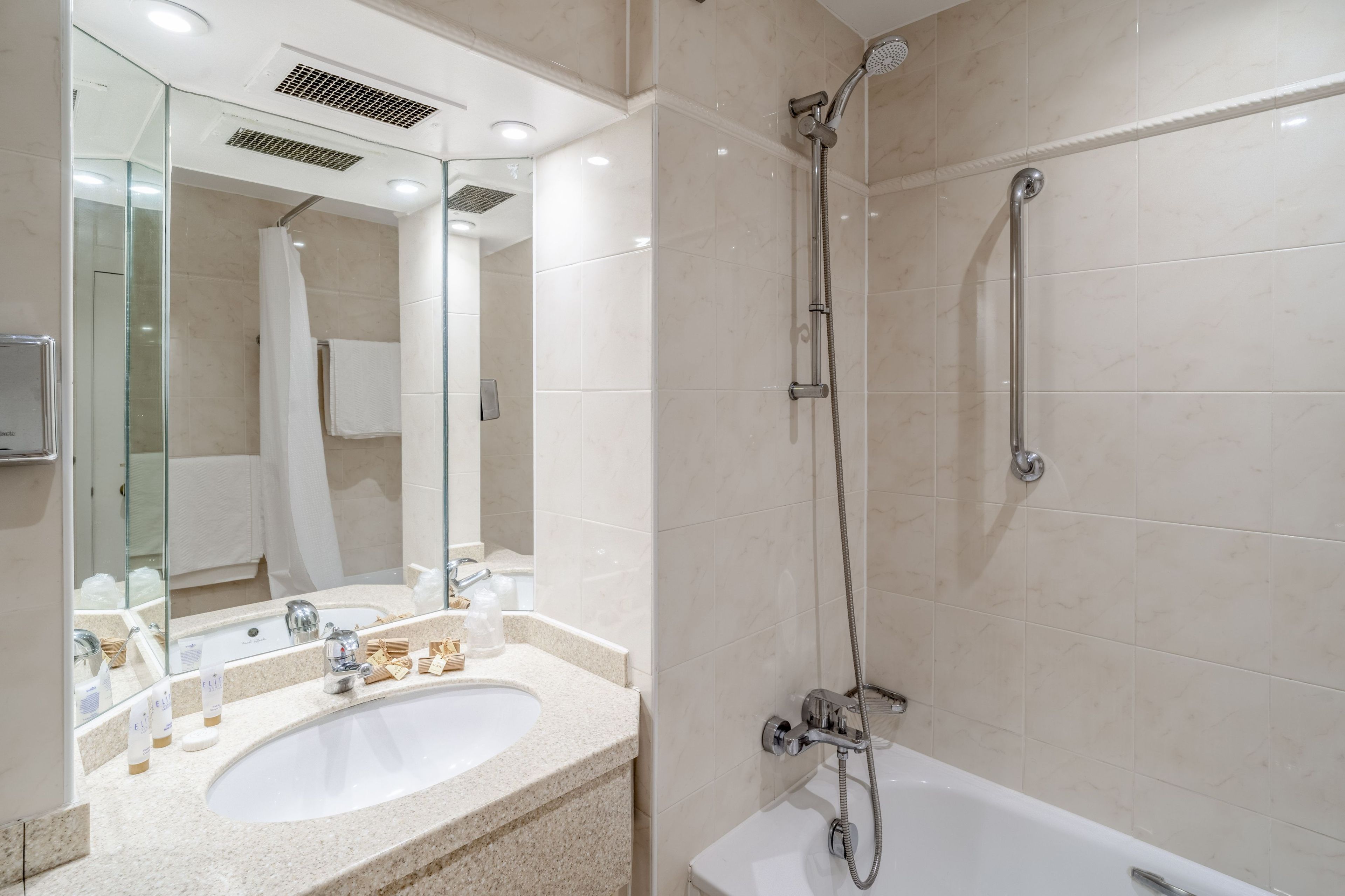 Un baño moderno con bañera, ducha, lavabo y espejo.