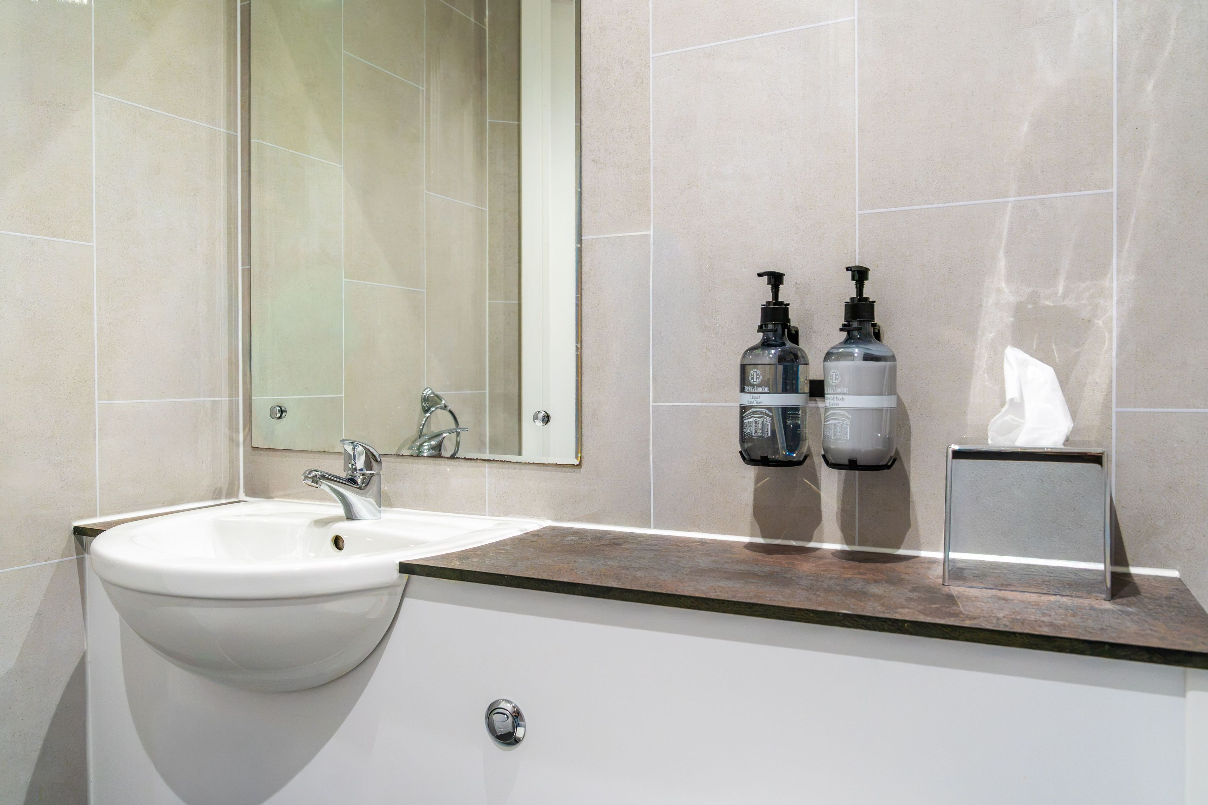 A bathroom with a white sink, a mirror, and two hand sanitizer dispensers.