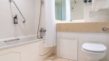 A bathroom with a bathtub, a toilet, and a shower area.