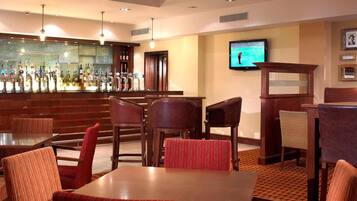 A bar area with multiple taps, a television mounted on the wall, and several seating arrangements including tables and chairs.