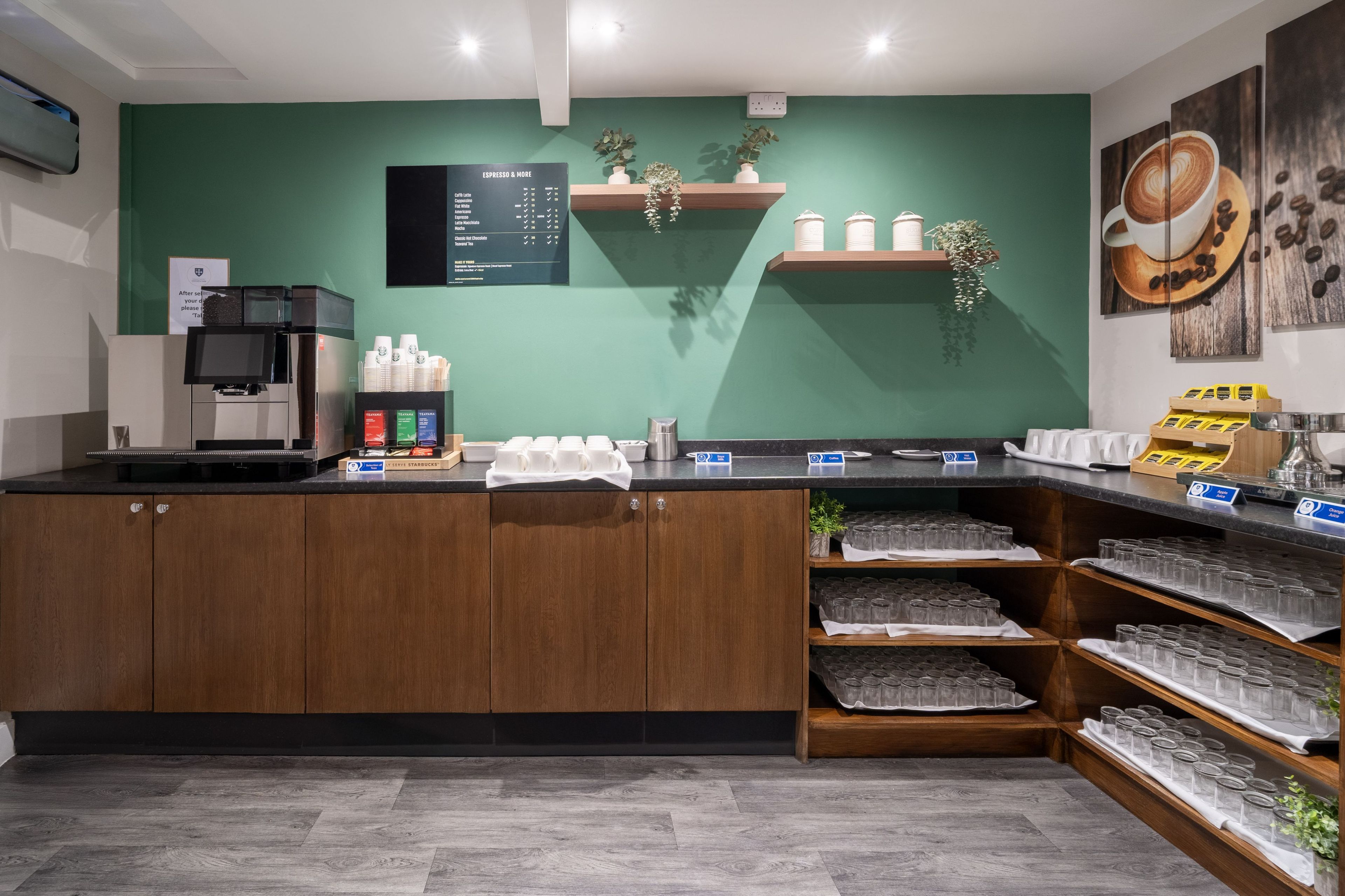 A coffee shop counter with a menu board, coffee machines, and shelves with coffee cups and jars.