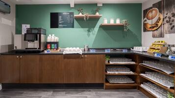 A coffee shop counter with a menu board, coffee machines, and shelves with coffee cups and jars.