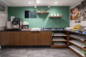 A coffee shop counter with a menu board, coffee machines, and shelves with coffee cups and jars. - Grand Hotel Gosforth Park (Newcastle-upon-Tyne)
