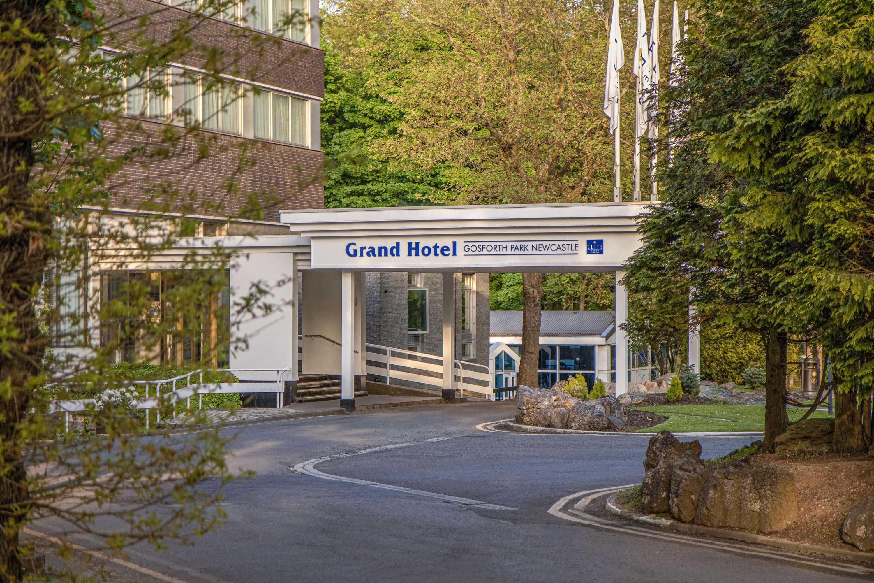 A hotel entrance with a sign reading 'Grand Hotel Gosforth Park Newcastle' and a modern building structure.