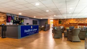 A reception area with a blue counter, wicker furniture, and a brick wall.