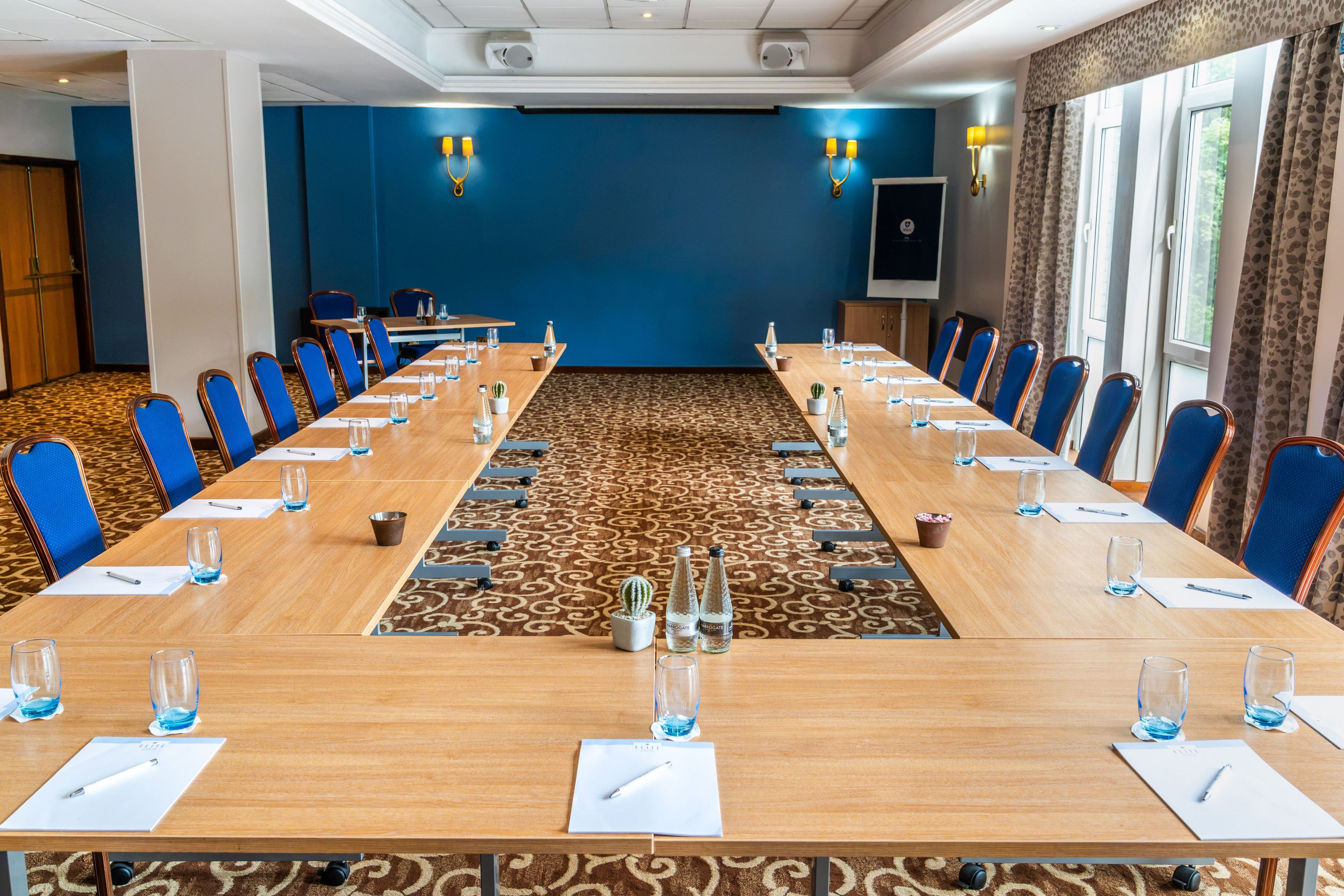 A conference room with a long table, chairs, and a carpeted floor.