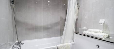 A modern bathroom with a bathtub, shower, and toilet.