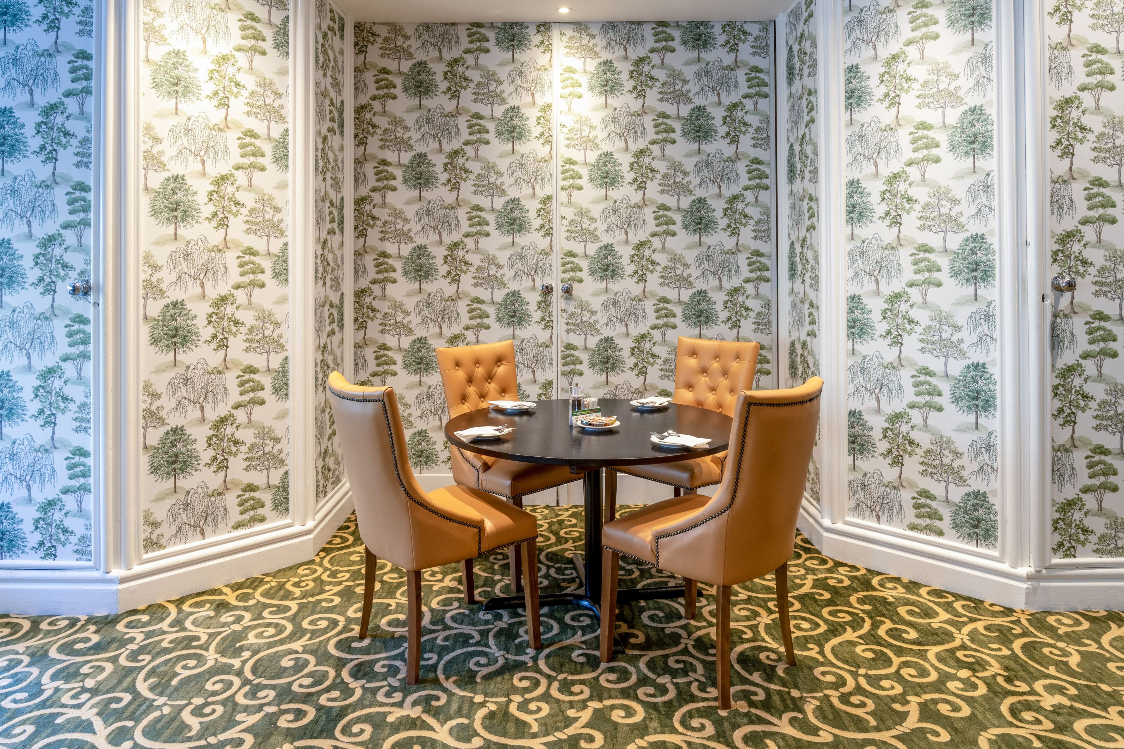 Un coin repas avec une table ronde, quatre chaises et un tapis à motifs.