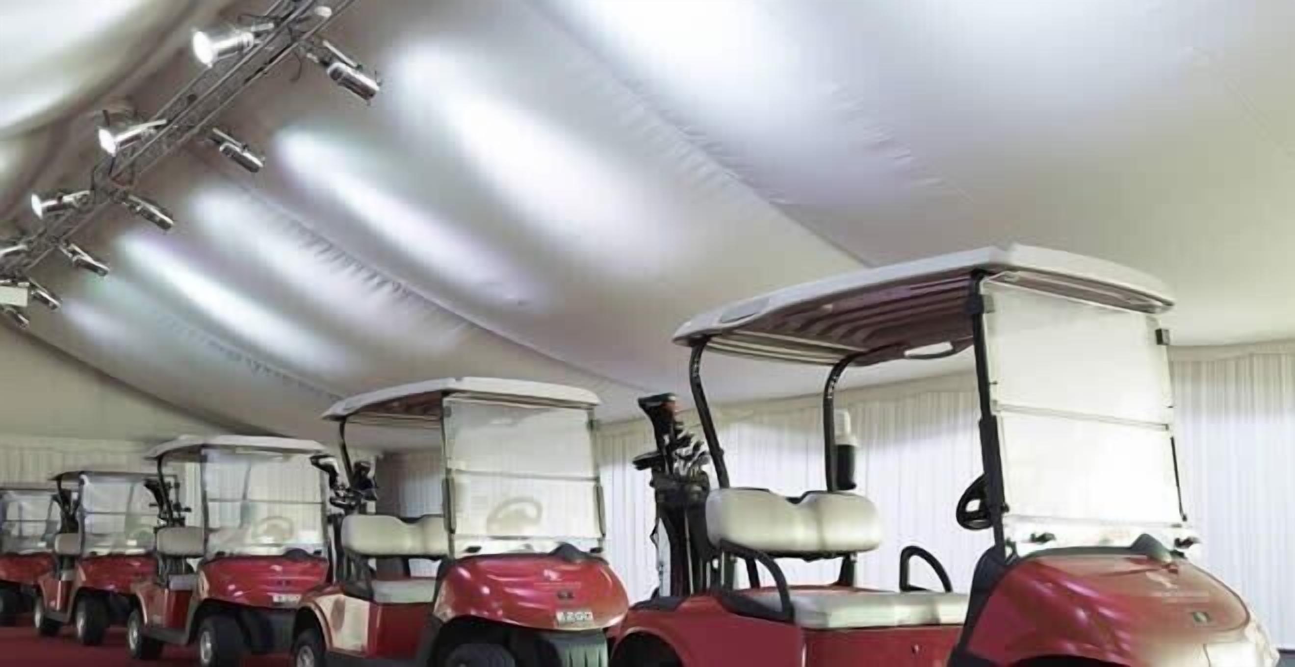 A row of red golf carts with white canopies parked indoors.