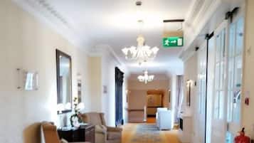 Un vestíbulo de hotel con una araña, una recepción y un extintor.