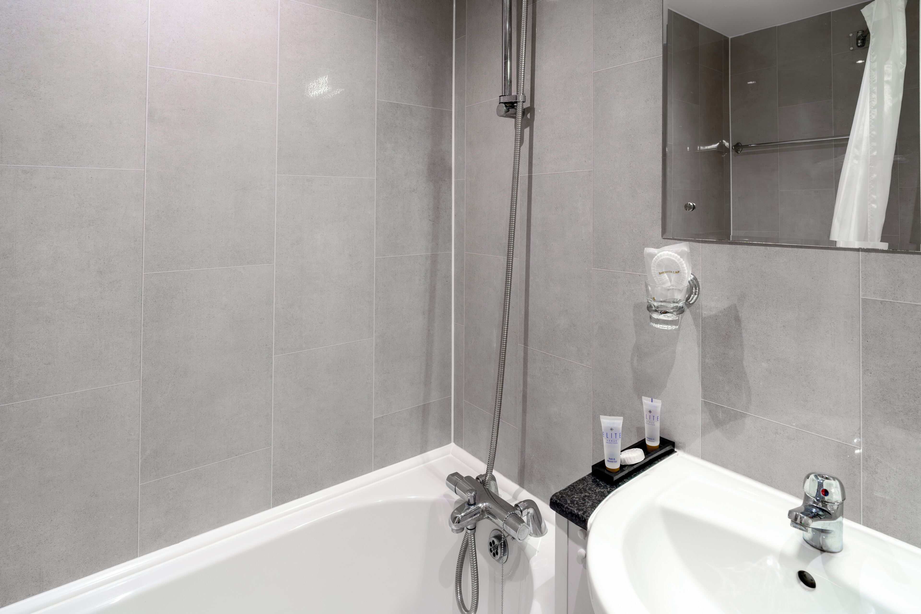 Een moderne badkamer met een bad, een douche, een wastafel en een spiegel.
