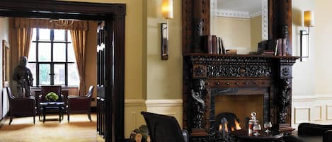 A room with a fireplace, a large mirror, and a view of a garden through a window.