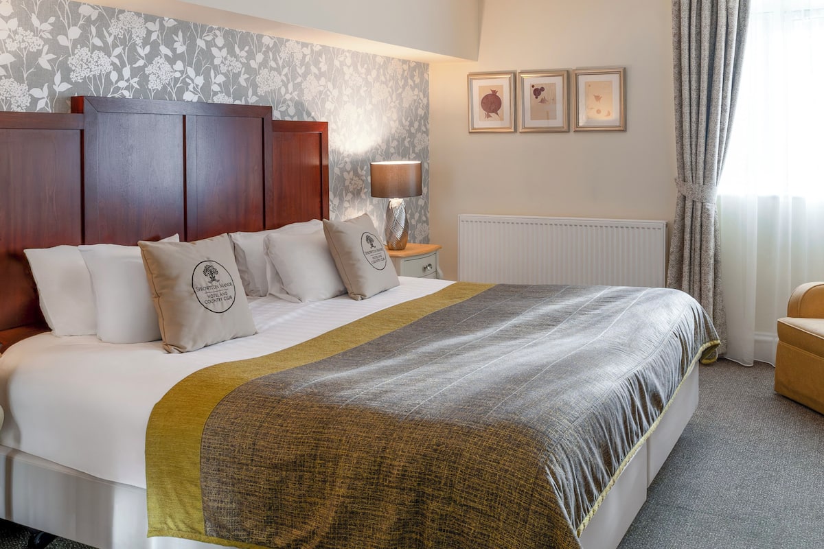 A neatly made bed with a headboard, a bedside lamp, and a radiator.